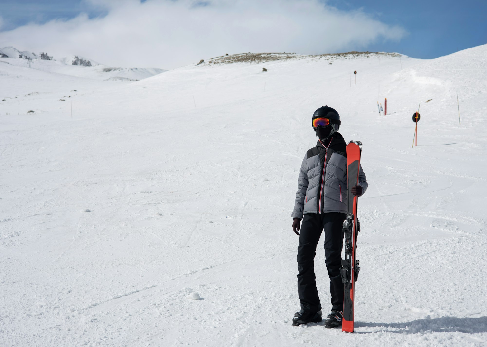 Girl in helmet and sunscreen with ountain ski stays on the snowy slope. Extreme sport and travel