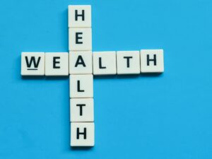 Wealth health word made from crossword square letter tiles on blue background.